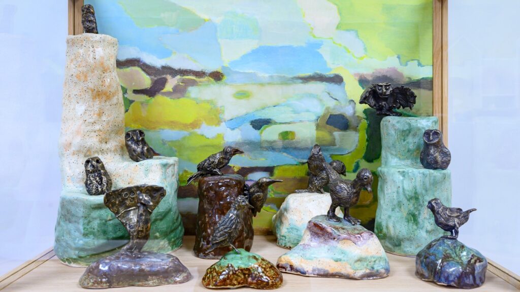 Colour photograph of a sculpture. The sculpture is made from small bronze birds.